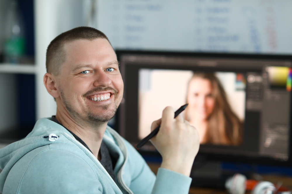 How to Master Remote Work: A smiling man with a pen and a laptop behind him