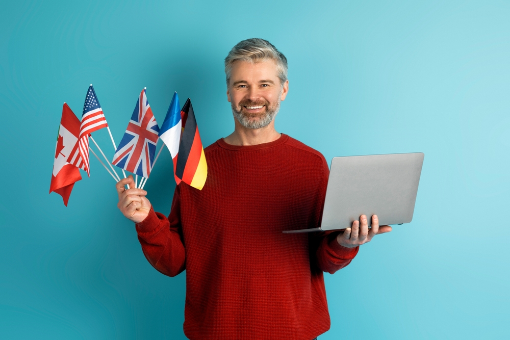 Digital Nomads Visa: A nomad worker holding flags of different countries in his right hand, while holding his laptop with his left hand
